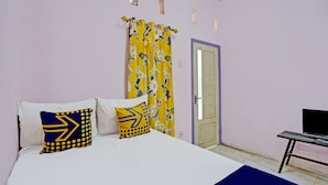 A bedroom with a bed, pillows, a TV, and a door. - Hotel O Kemangi Asri Kost (Banyuwangi)