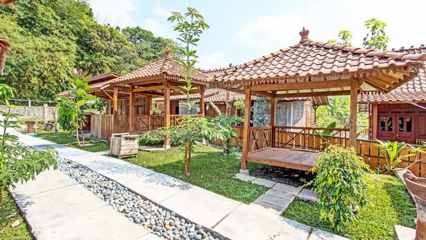 A traditional wooden pavilion with a tiled roof, surrounded by a well-maintained garden with a gravel pathway. - Collection O 91582 Green Kasongan Cottage (Kasihan)