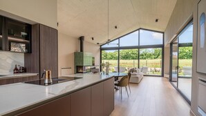 A modern kitchen with a large island, a built-in stove, and a view of a garden through large windows. - Stunning home in Bale (Bale)