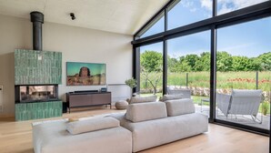A modern living room with a large window, a fireplace, a sofa, and a painting. - Stunning home in Bale (Bale)