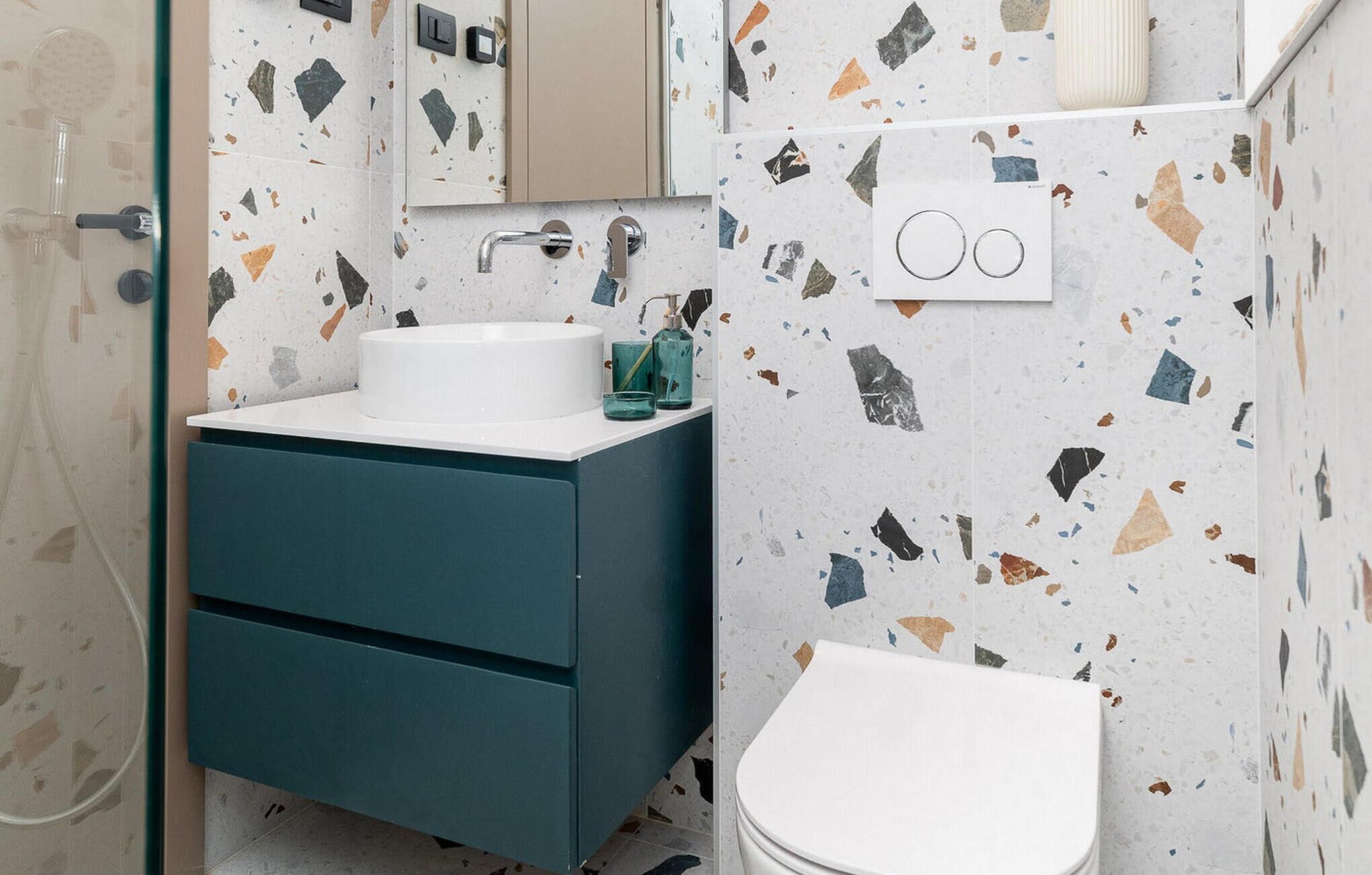 Un baño con un lavabo blanco, un mueble azul y un inodoro blanco.
