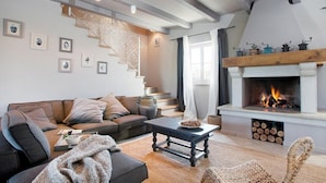 Ein gemütliches Wohnzimmer mit Kamin, Treppe und einer Couch.