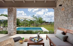 Relax by the pool in a serene outdoor space with a wicker chair, wooden bench, and small table.