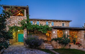 A stone building with a green door, multiple windows, and a well-lit entrance. - Beautiful home in Grandici (Grandici)