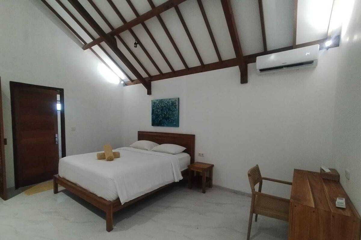 A bedroom with a wooden bed, a nightstand, a chair, and a ceiling fan.