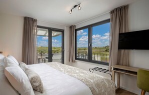 Relax in this serene hotel room with a large bed, balcony, and stunning views of the surrounding landscape.