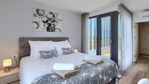 Ein modernes Hotelzimmer mit einem großen Bett, Blick ins Freie und einem Gemälde an der Wand.