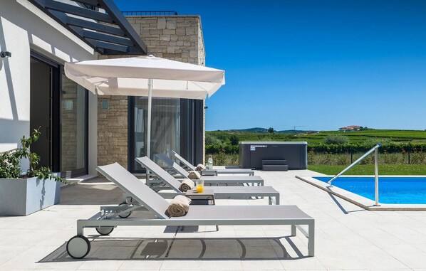 Relax by the pool with a clear view of the surrounding landscape, lounge chairs, and a flat-screen TV.