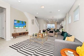 A modern living room with a sofa, coffee table, and a large painting of a beach scene.