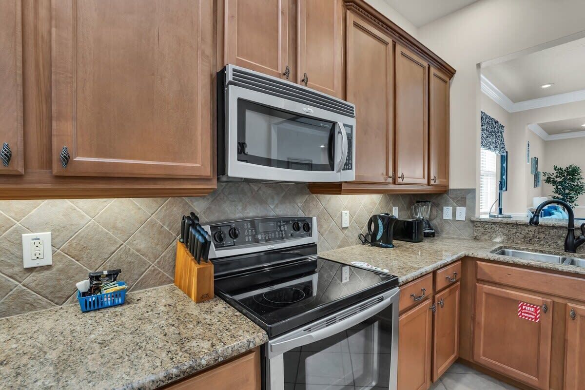 A kitchen with wooden cabinets, a microwave, a stove, and a sink.