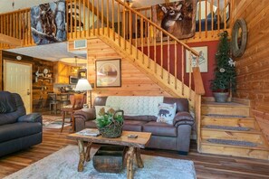 A wooden interior with a staircase, a sofa, a coffee table, and a fireplace. - Creekside Oasis| Pet-Friendly|Cottage with River (Cleveland)