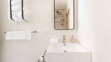 Un baño moderno con un lavabo blanco, un espejo y un perchero para toallas.