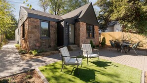 Een stenen huis met een terras, twee stoelen en een tafel.