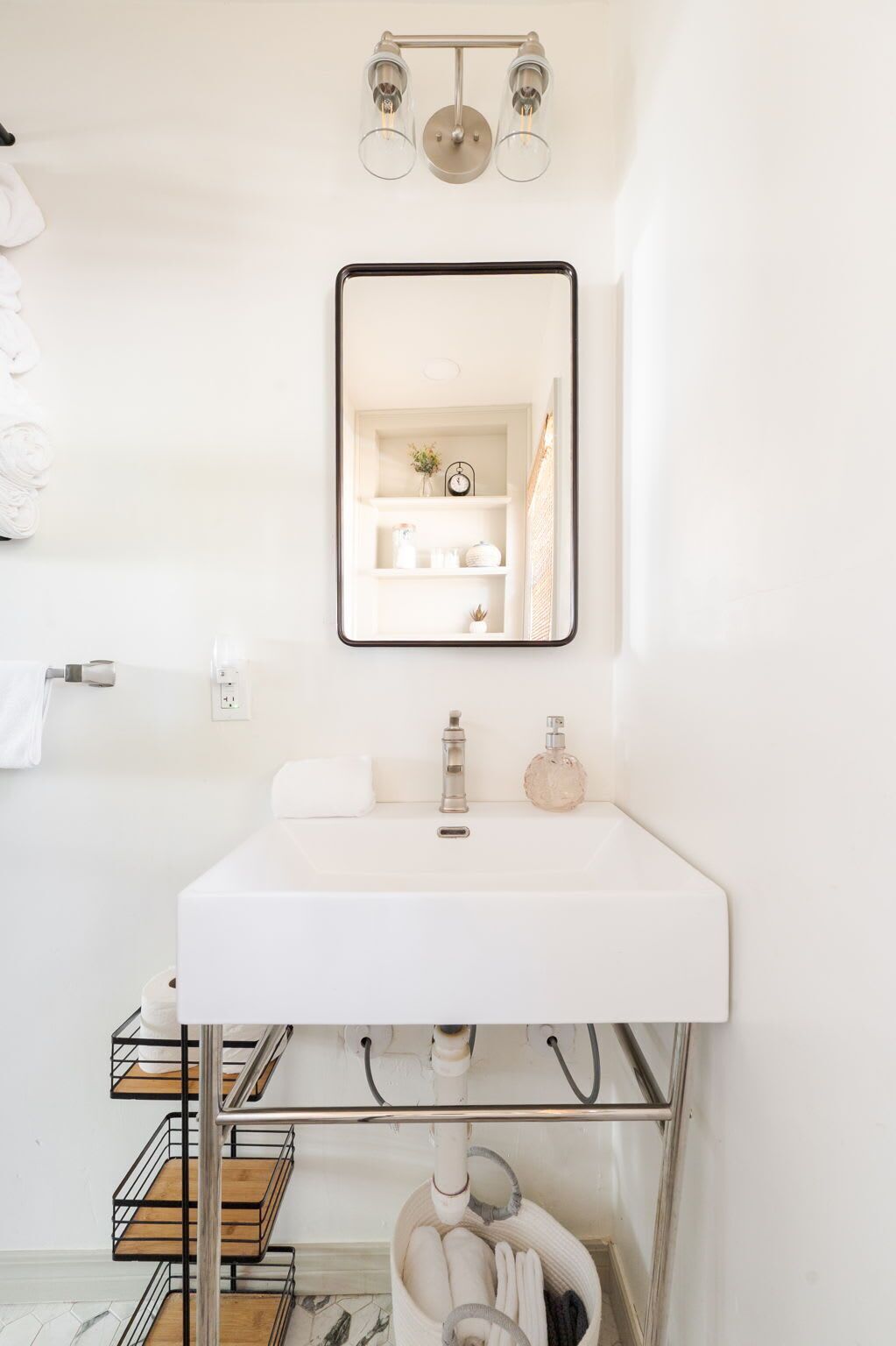 Une salle de bain moderne avec un lavabo blanc, un miroir et un porte-serviettes.