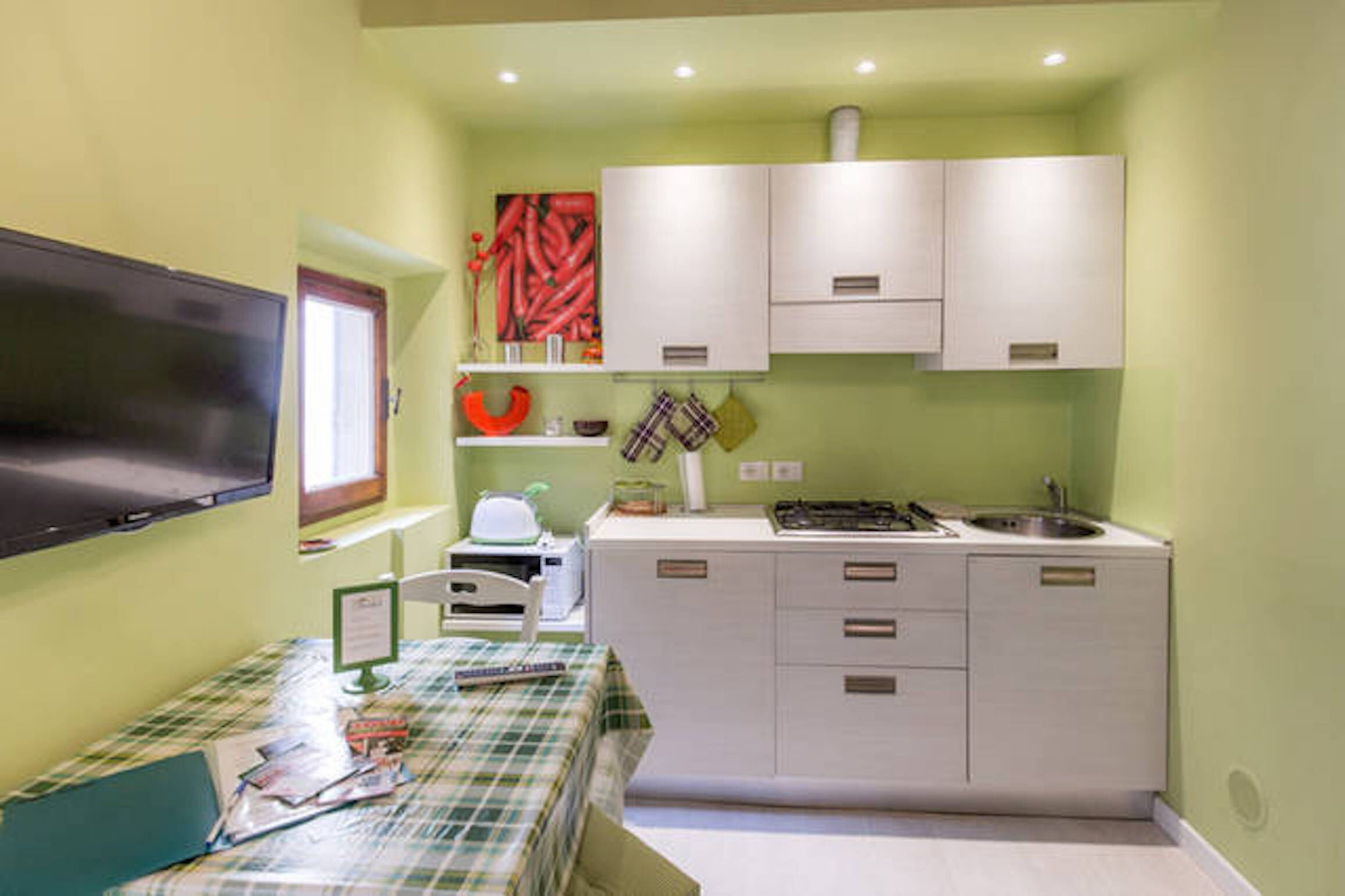 Una cocina compacta con armarios blancos, una estufa y un lavamanos.