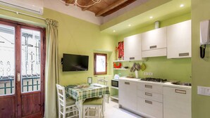 A kitchen with white cabinets, a dining table with a checkered tablecloth, and a television on the wall. - 1BR Apt in Via Panicale by Sea N' Rent (Florence)