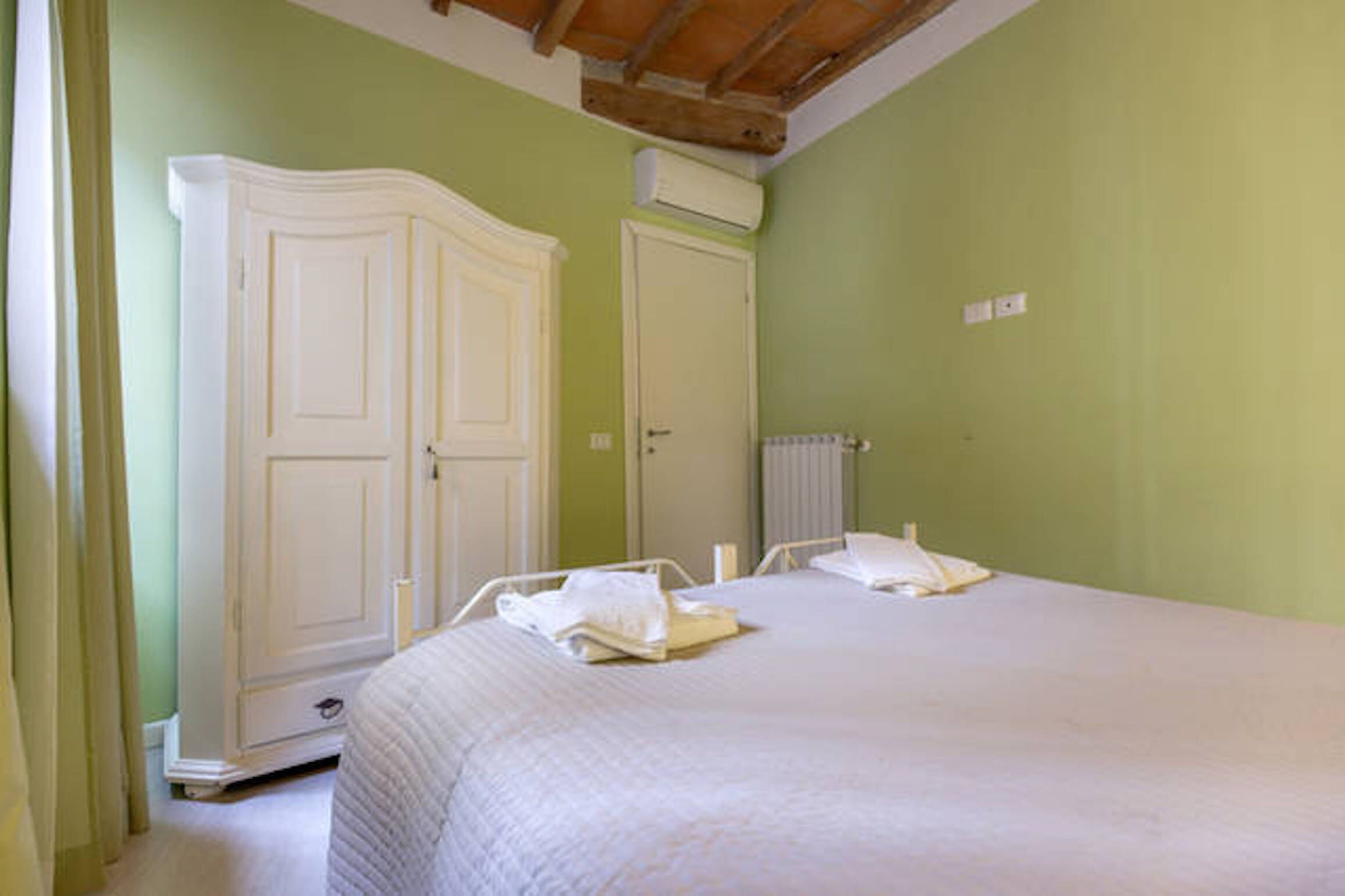 Un dormitorio con una cama grande, dos armarios y un radiador.