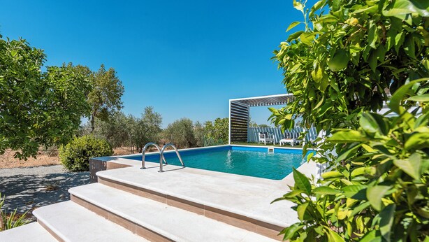 A swimming pool with steps leading into it, surrounded by greenery and a clear blue sky. - Holiday Home Adalid, Seville Countryside (La Puebla de Cazalla)