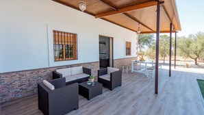 A covered outdoor seating area with wicker furniture and a table, a wooden ceiling, and a view of the surrounding landscape. - Holiday Home Adalid, Seville Countryside (La Puebla de Cazalla)