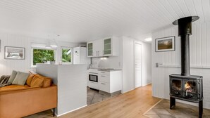 Una cocina moderna con armarios blancos, un horno empotrado y una estufa de leña negra.