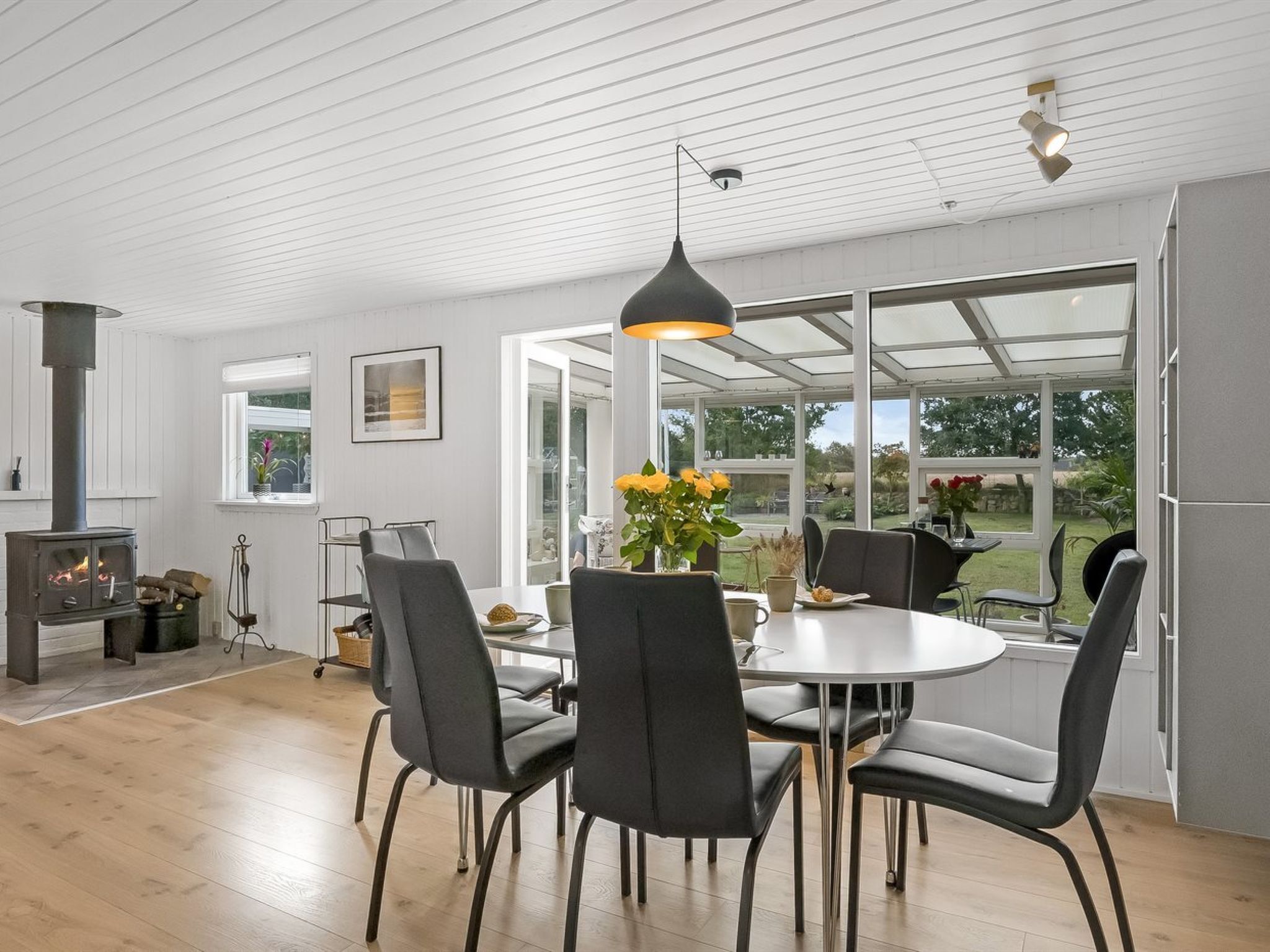 A modern dining area with a round table, black chairs, and a large window offering a view of the outdoors.