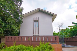A modern building with a flat roof, a central vertical window, and a gated entrance. - Hotel O Putri Guest House Syariah Near SPBU Rimbo Panjang (Pekanbaru)