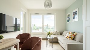 A modern living room with a sofa, a dining table, and a TV. - RentPlanet - Apartamenty Zajezdnia (Wroclaw)