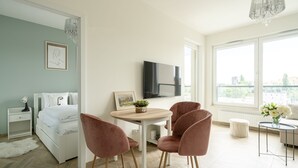 A modern bedroom with a bed, a TV, a dining table, and chairs. - RentPlanet - Apartamenty Zajezdnia (Wroclaw)