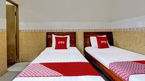 Ein Hotelzimmer mit zwei Betten, jeweils mit einer roten und weißen Tagesdecke und passenden Kissen.