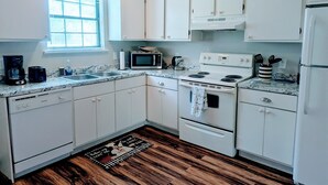 Une cuisine avec des meubles blancs, un four à micro-ondes, une cuisinière et un réfrigérateur.