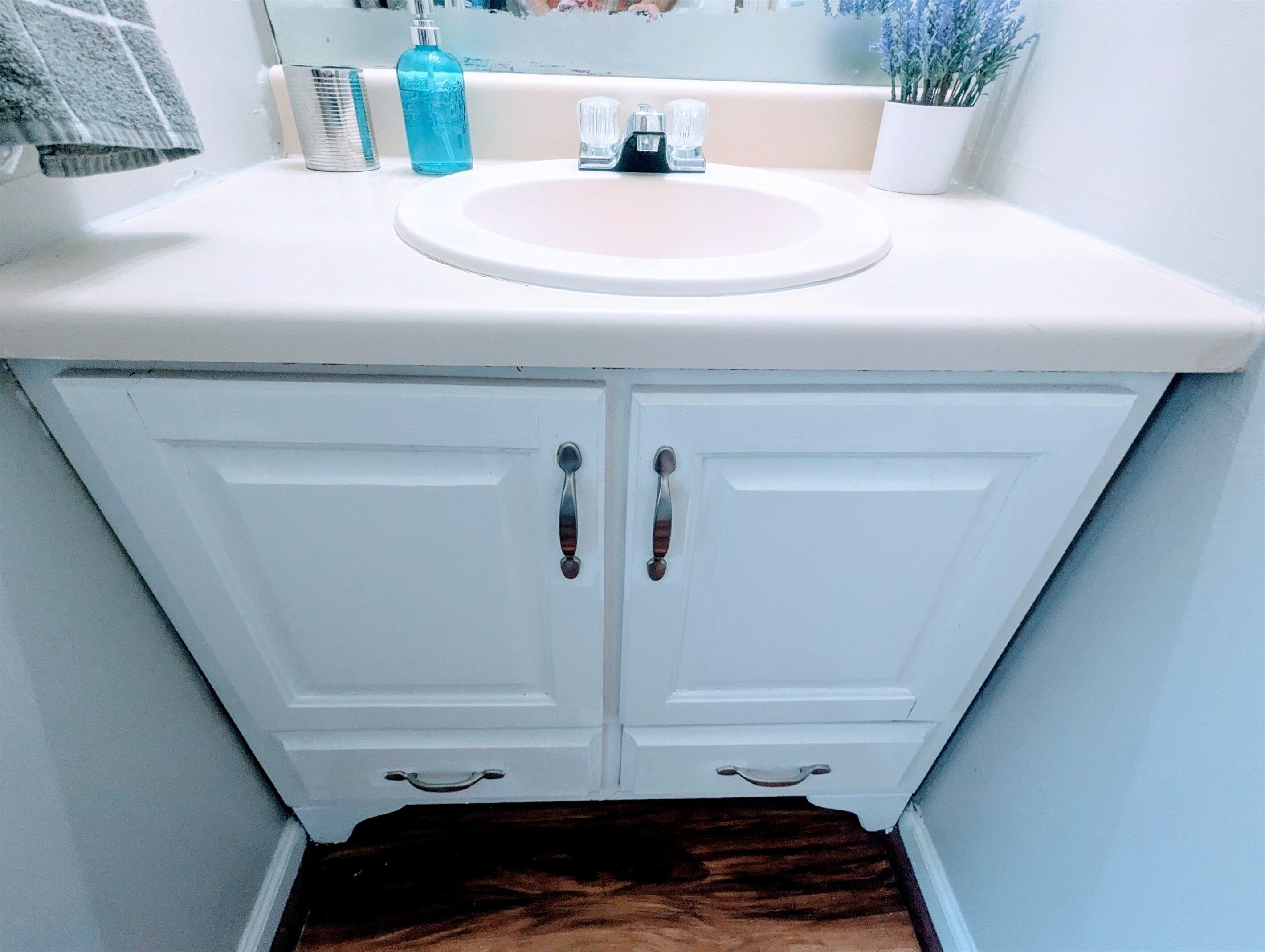 Un meuble-lavabo blanc pour la salle de bain, doté d’un évier, de deux portes et d’un miroir.