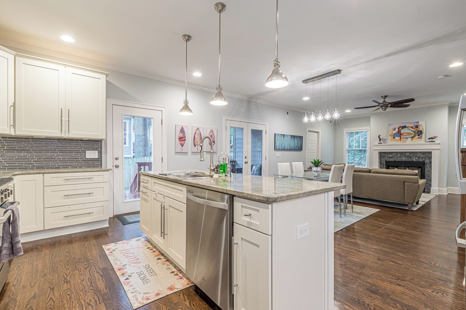 A modern kitchen with white cabinets, stainless steel appliances, and pendant lighting.