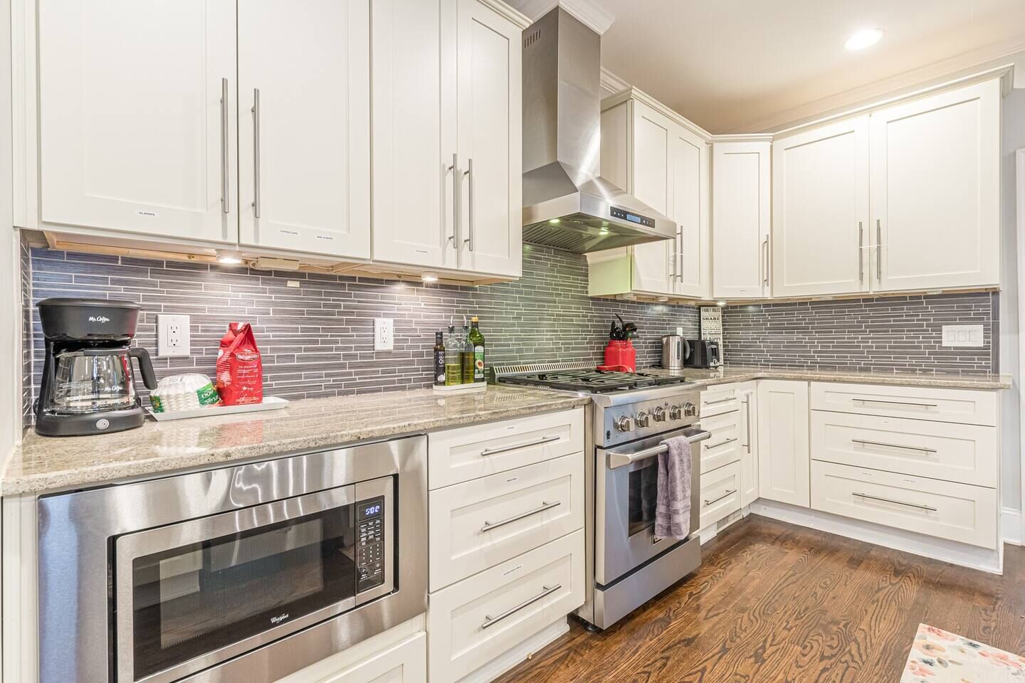 A modern kitchen with white cabinets, stainless steel appliances, and a tiled backsplash.