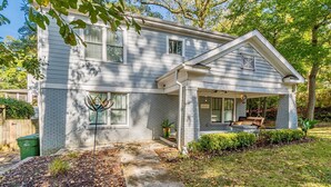 A two-story house with a covered porch, a brick exterior, and a small garden area. - Modern, Walkable Family Home w/ Porch & Parking (Atlanta)