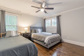 Une chambre avec deux lits, un ventilateur de plafond et une table de chevet avec une lampe.