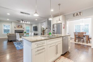 A modern kitchen with white cabinetry, a central island, stainless steel appliances, and pendant lighting.