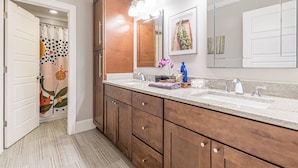 A modern bathroom with wooden cabinets, a double sink, and a large mirror. - Modern, Walkable Family Home w/ Porch & Parking (Atlanta)