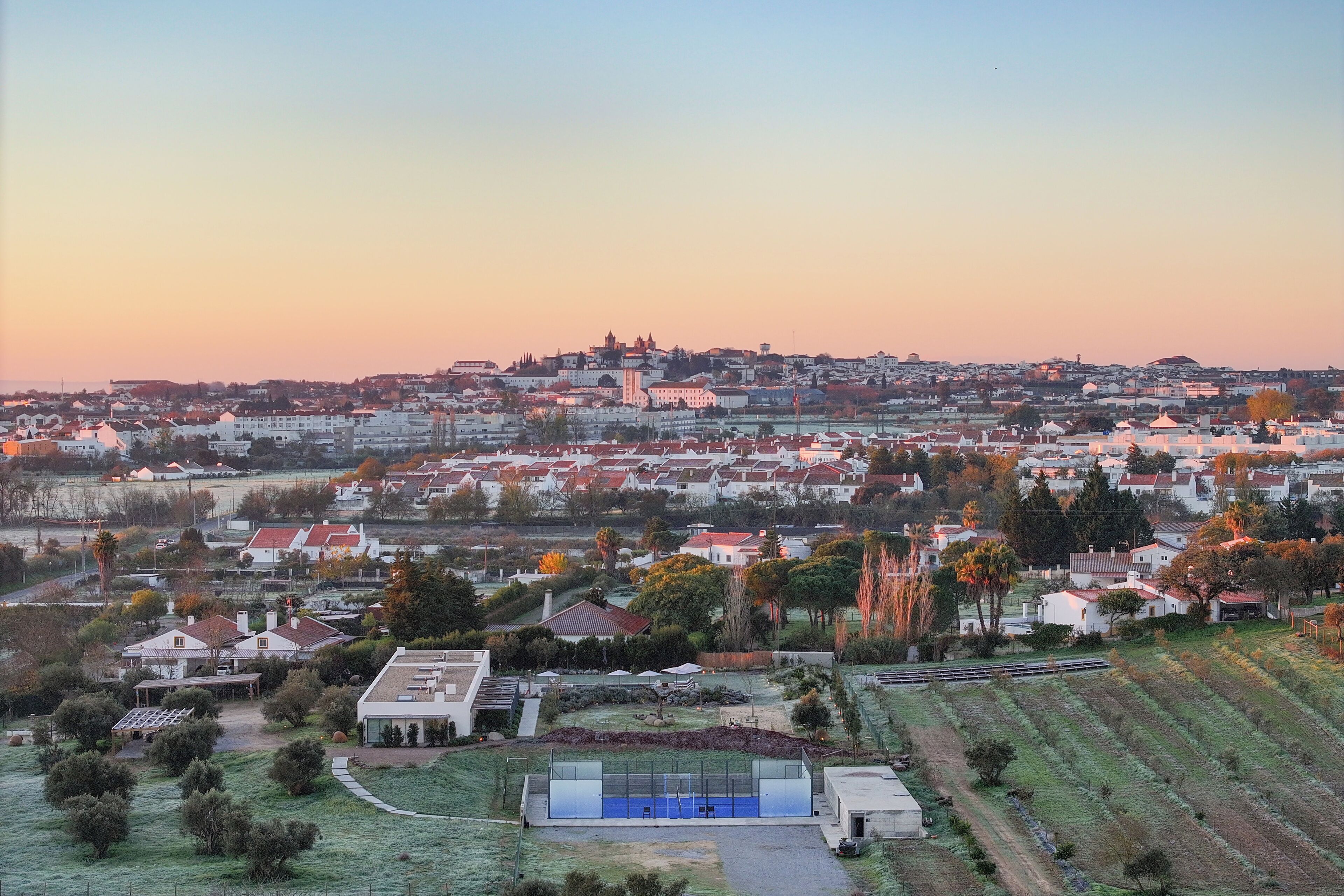 Uma área residencial com casas, um edifício grande com cúpula e uma quadra de tênis.
