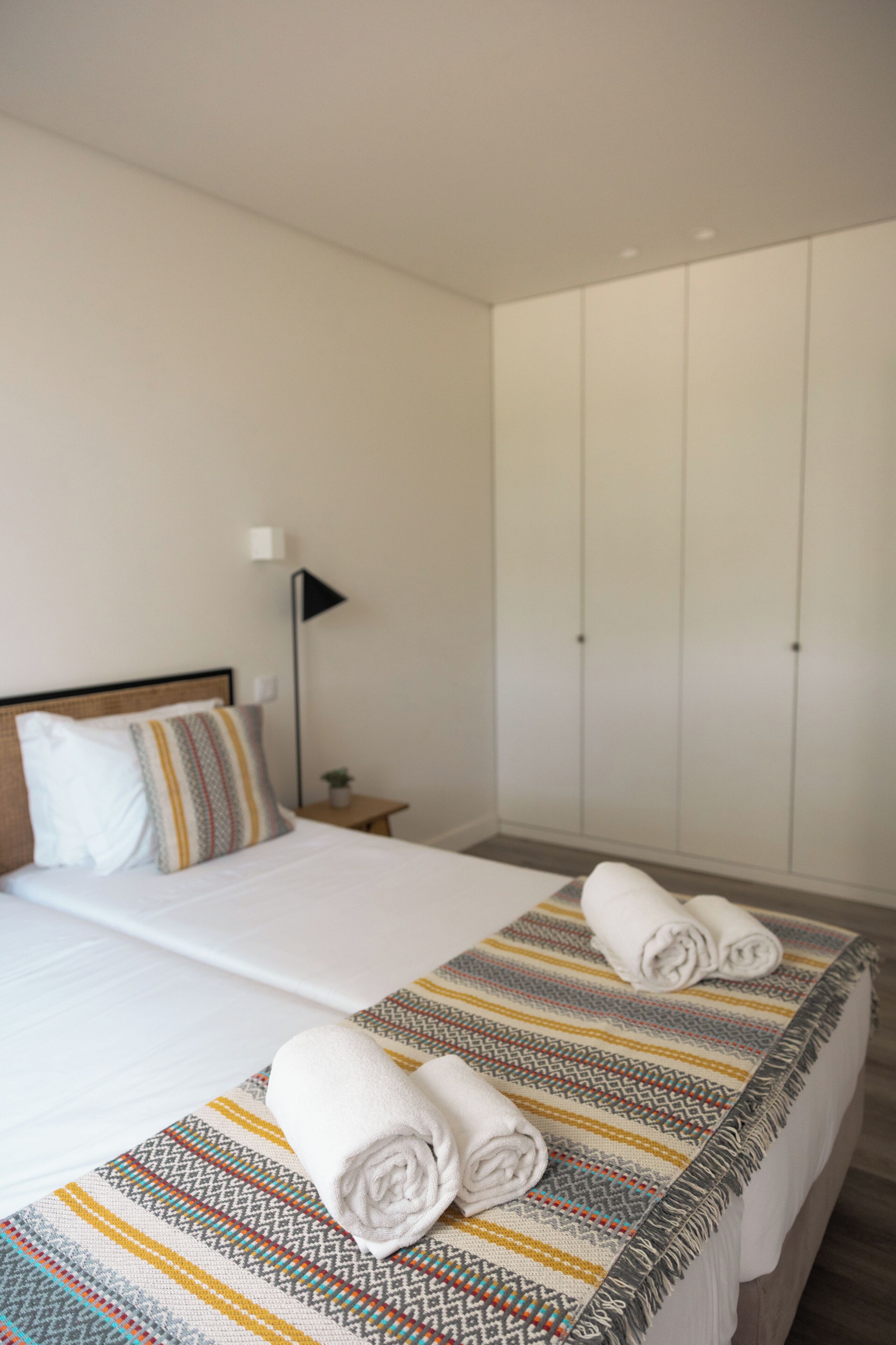 Une chambre d’hôtel avec un lit, une table de chevet, une lampe et une armoire.