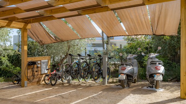 A covered parking area with bicycles and scooters.