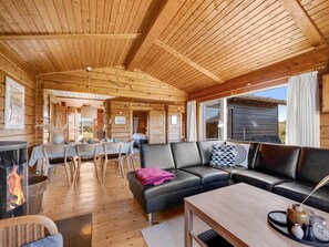 A cozy cabin interior with a fireplace, a dining area, and a living room with a sofa and a coffee table.
