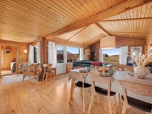L’intérieur d’un chalet en bois comprend un coin repas, un canapé et offre une vue sur l’extérieur.