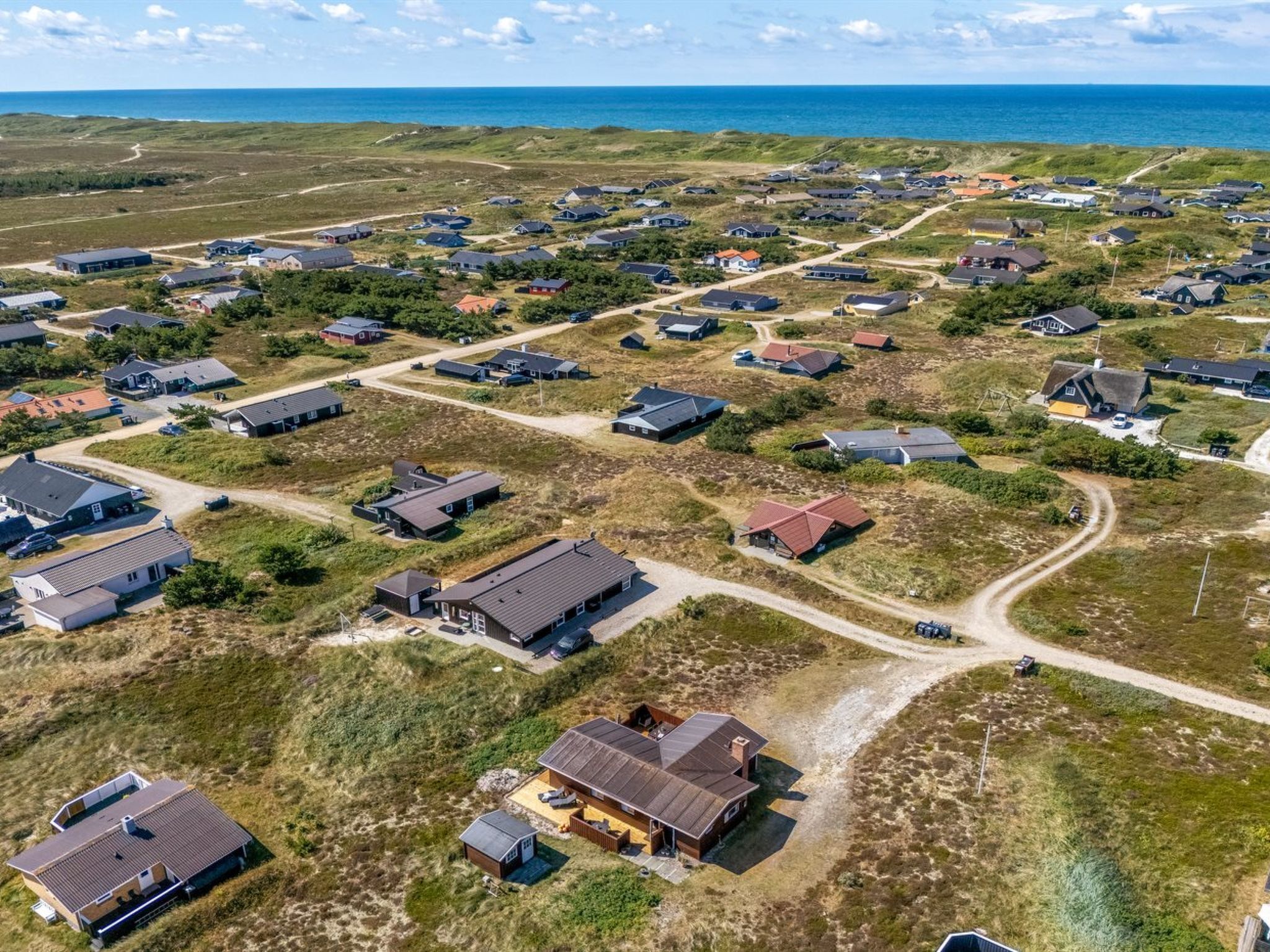 An aerial view of a coastal residential area with houses, roads, and a beach.