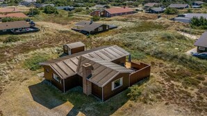 A single-story house with a large deck and a chimney, surrounded by a grassy landscape. - "Evelin" -  from the sea by Interhome (Hvide Sande)