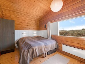 Une chambre à coucher avec un lit, une fenêtre et des murs en bois.