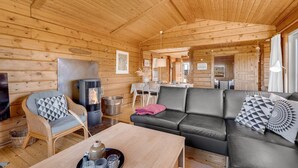 A cozy log cabin interior with a sofa, a dining area, and a fireplace. - "Evelin" -  from the sea by Interhome (Hvide Sande)