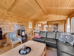 Un accogliente interno di una baita in legno, con un divano, un'area pranzo e un camino.