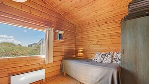 A wooden cabin bedroom with a bed, a window, and a radiator. - "Evelin" -  from the sea by Interhome (Hvide Sande)