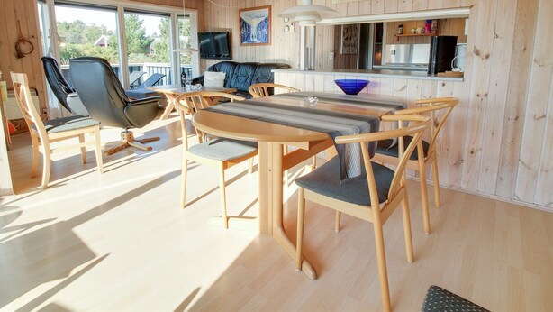 A modern, open-plan living space with a wooden interior, a dining area, and a kitchen.
