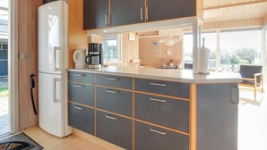 A modern kitchen with a built-in refrigerator, a coffee maker, and a large window providing natural light.